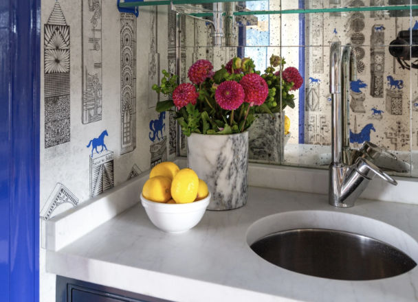 A blue and white bar with custom chrome bar rods and a marble counter top. blue and white Jennifer Shorto horse wallpaper adorns the walls of a wet bar leading into a blue and pink dining room by jewel Marlowe. Luxury design, colorful design, famous designer, washington dc, virginia, maryland